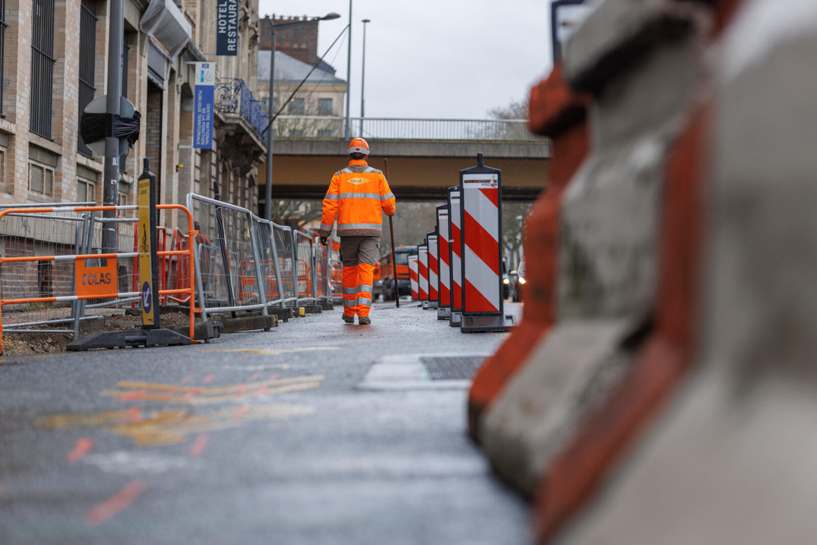 Un ouvrier du bâtiment en tenue de sécurité orange se déplace sur un chantier