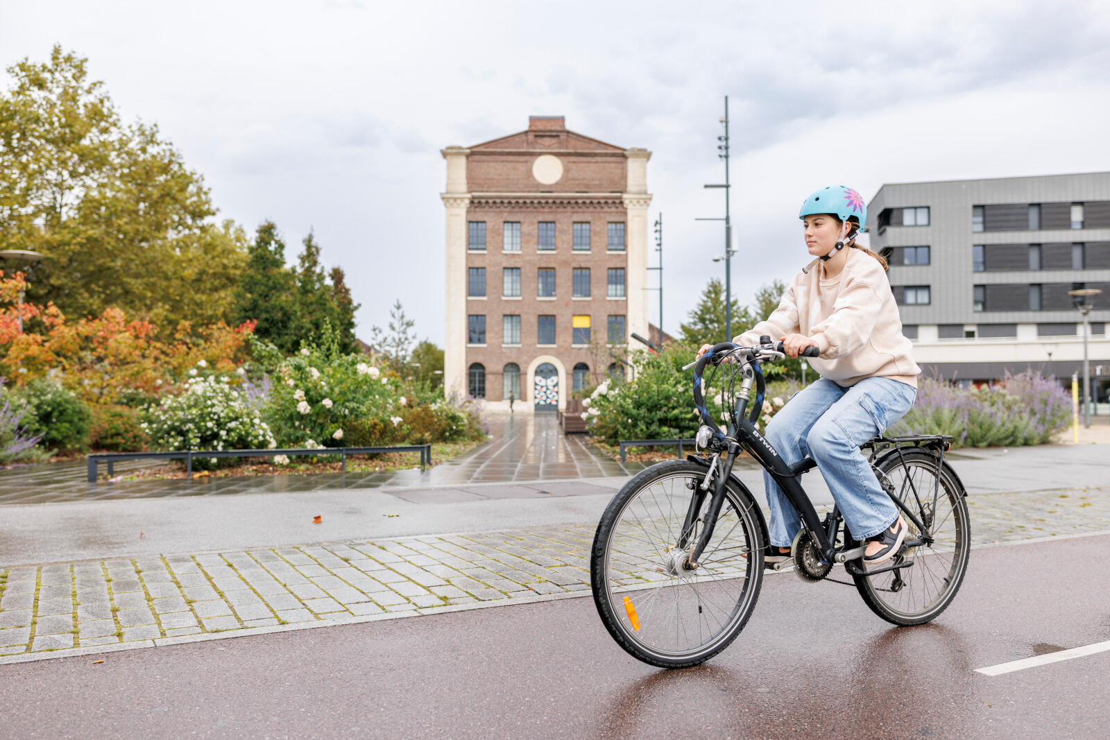 Une personne en vélo, équipée d’un casque, circule sur une piste cyclable.