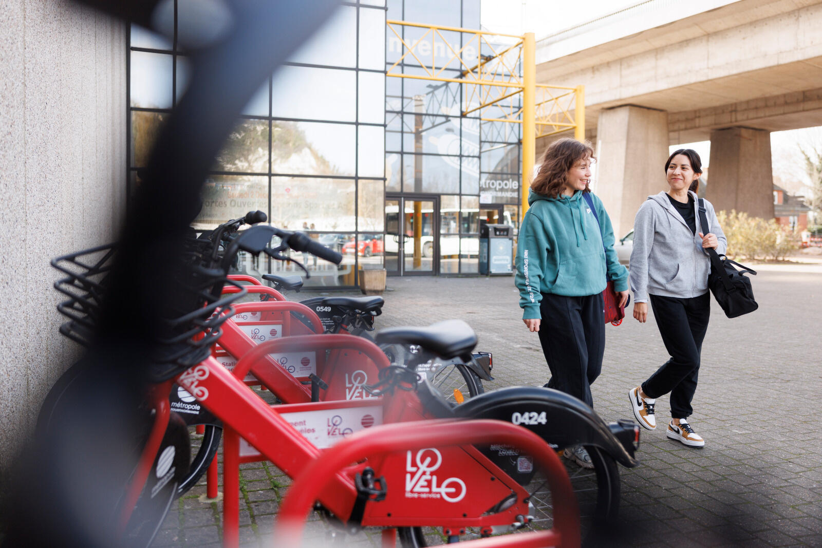Deux femmes se tiennent à côté de vélos Lovélo garés en libre-service