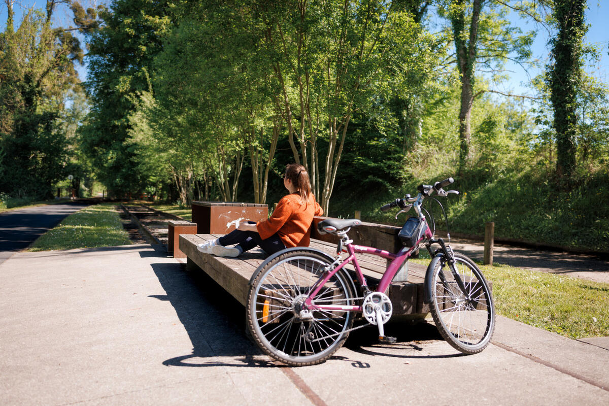 Une personne se repose sur un banc près de son vélo