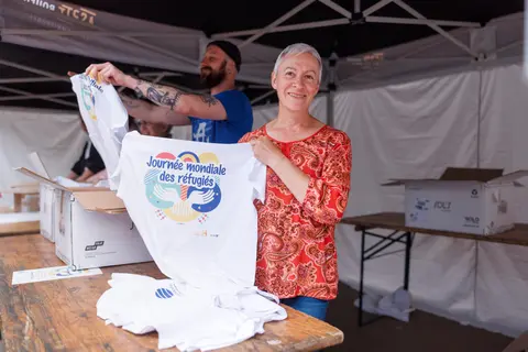 Une dame montre un tee-shirt avec le logo de l'opération