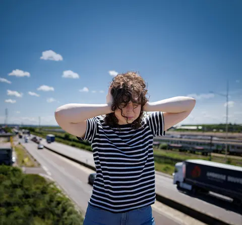 Jeune femme se bouchant les oreilles près d'une route